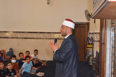 Kahire, Mısır, 31 Mayıs 2022: Cami vaizi İmam, camideki çocuklara yönelik yaz İslami eğitim programı sırasında camide genç Müslüman çocuklara vaaz veriyor.