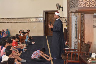 Kahire, Mısır, 31 Mayıs 2022: Cami vaizi İmam, camideki çocuklara yönelik yaz İslami eğitim programı sırasında camide genç Müslüman çocuklara vaaz veriyor.