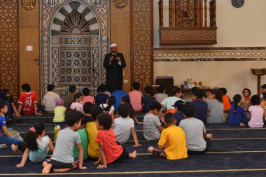 Kahire, Mısır, 31 Mayıs 2022: Cami vaizi İmam, camideki çocuklara yönelik yaz İslami eğitim programı sırasında camide genç Müslüman çocuklara vaaz veriyor.