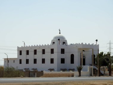 Karayolu kenarında, beyaz bir kubbe ve açık gökyüzü olan beyaz bir mescit... İnananların Allah 'a dua edecekleri bir mescit...