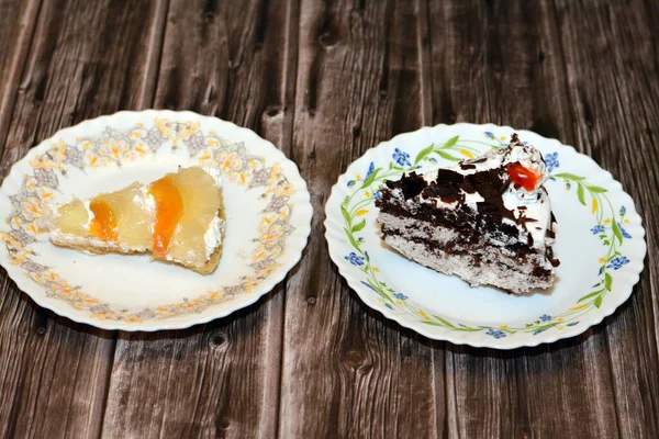 Dilimlenmiş bir parça kara orman pastası, çırpılmış krema ve kiraz katmanlı çikolatalı kek ve ahşap bir zeminde taze meyveli bir dilim tropikal meyveli kek.