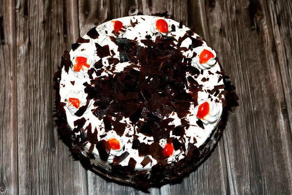 A black forest cake, a light chocolate sponge cake, soaked with cherry syrup and cherry brandy (Kirsch), then layered with whipped cream and cherries isolated on a wooden background, selective focus