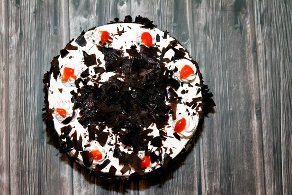 A black forest cake, a light chocolate sponge cake, soaked with cherry syrup and cherry brandy (Kirsch), then layered with whipped cream and cherries isolated on a wooden background, selective focus