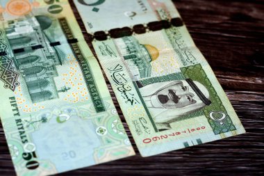 Suudi Arabistan 50 SAR 50 Suudi para banknotu Kral Abdullah Bin AbdulAziz ve Kubbe of the Rock ve El Aksa camiinin fotoğrafı ile seçici bir odaklı ahşap arka planda izole edilmiş.