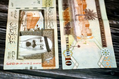 Suudi Arabistan 10 SAR 10 Suudi para banknotu Kral Abdullah, Murabba Sarayı ve Kral AbdulAziz 'in fotoğrafı ile tahtadan bir arka planda izole edilmiş, seçici bir odak