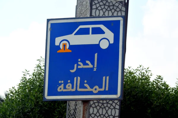 Translation of Arabic inscription (Beware of traffic violation), a traffic sign indicates a restricted area for parking the vehicles and a car with a locked wheel symbol, selective focus