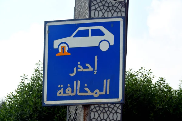 Translation of Arabic inscription (Beware of traffic violation), a traffic sign indicates a restricted area for parking the vehicles and a car with a locked wheel symbol, selective focus