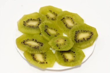 Bir tabak dilimlenmiş kiwifruit 'in seçici odak noktası, Çin bektaşi üzümü, beyaz arka planda izole edilmiş çeşitli ahşap üzümlerin yenilebilir üzümleridir, Kiwi' nin tatlı aromalı yumuşak bir dokusu vardır.