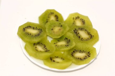 Bir tabak dilimlenmiş kiwifruit 'in seçici odak noktası, Çin bektaşi üzümü, beyaz arka planda izole edilmiş çeşitli ahşap üzümlerin yenilebilir üzümleridir, Kiwi' nin tatlı aromalı yumuşak bir dokusu vardır.