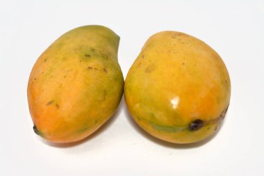 Beyaz zemin üzerinde izole edilmiş taze mango meyvesinin seçici odak noktası, tropikal ağaç Mangifera indikası tarafından üretilen ve boyut, şekil, tatlılık ve renk olarak değişen yenilebilir bir taş meyvedir.