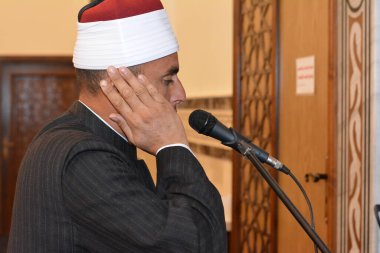 Cairo, Egypt, July 27 2022: A mosque Imam preacher muezzin in front of the microphone reciting Adhan Azan or calling loudly for the prayer or Salah summoning Muslims to enter the mosque for prayer