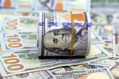 100 dolarlık banknotlar yığını üzerinde bir tomar para, 100 dolarlık nakit para yığını lastik bantla sarılmış Benjamin Franklin 'in portresi, seçici odaklı