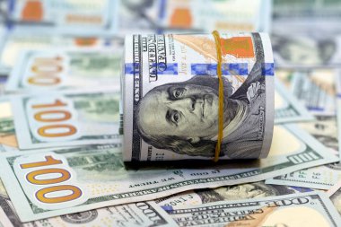 100 dolarlık banknotlar yığını üzerinde bir tomar para, 100 dolarlık nakit para yığını lastik bantla sarılmış Benjamin Franklin 'in portresi, seçici odaklı