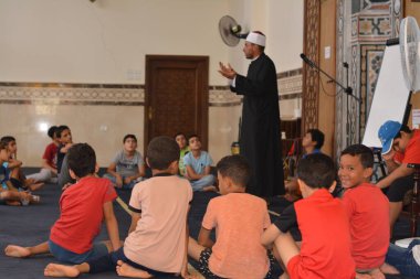 Cairo, Egypt, August 7 2022: A mosque preacher Imam performs a religious Khutbah (sermon) for young Muslim children inside a mosque during the summer Islamic educational program for kids in the mosque