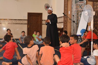 Cairo, Egypt, August 7 2022: A mosque preacher Imam performs a religious Khutbah (sermon) for young Muslim children inside a mosque during the summer Islamic educational program for kids in the mosque