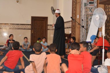 Cairo, Egypt, August 7 2022: A mosque preacher Imam performs a religious Khutbah (sermon) for young Muslim children inside a mosque during the summer Islamic educational program for kids in the mosque
