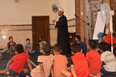 Cairo, Egypt, August 7 2022: A mosque preacher Imam performs a religious Khutbah (sermon) for young Muslim children inside a mosque during the summer Islamic educational program for kids in the mosque