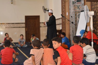 Cairo, Egypt, August 7 2022: A mosque preacher Imam performs a religious Khutbah (sermon) for young Muslim children inside a mosque during the summer Islamic educational program for kids in the mosque