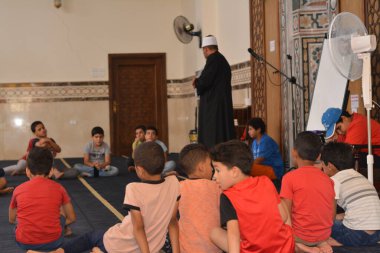 Cairo, Egypt, August 7 2022: A mosque preacher Imam performs a religious Khutbah (sermon) for young Muslim children inside a mosque during the summer Islamic educational program for kids in the mosque