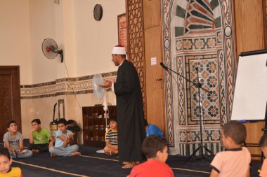 Cairo, Egypt, August 7 2022: A mosque preacher Imam performs a religious Khutbah (sermon) for young Muslim children inside a mosque during the summer Islamic educational program for kids in the mosque