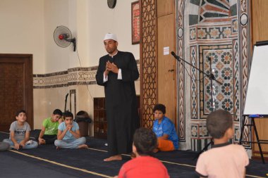 Cairo, Egypt, August 7 2022: A mosque preacher Imam performs a religious Khutbah (sermon) for young Muslim children inside a mosque during the summer Islamic educational program for kids in the mosque