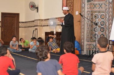 Cairo, Egypt, August 7 2022: A mosque preacher Imam performs a religious Khutbah (sermon) for young Muslim children inside a mosque during the summer Islamic educational program for kids in the mosque