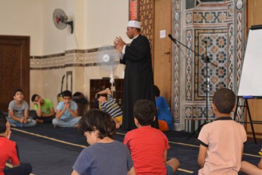 Cairo, Egypt, August 7 2022: A mosque preacher Imam performs a religious Khutbah (sermon) for young Muslim children inside a mosque during the summer Islamic educational program for kids in the mosque