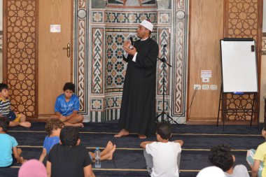 Cairo, Egypt, August 7 2022: A mosque preacher Imam performs a religious Khutbah (sermon) for young Muslim children inside a mosque during the summer Islamic educational program for kids in the mosque