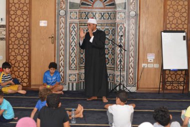 Cairo, Egypt, August 7 2022: A mosque preacher Imam performs a religious Khutbah (sermon) for young Muslim children inside a mosque during the summer Islamic educational program for kids in the mosque