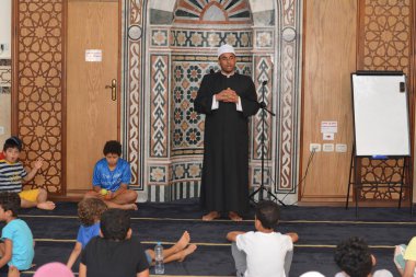 Cairo, Egypt, August 7 2022: A mosque preacher Imam performs a religious Khutbah (sermon) for young Muslim children inside a mosque during the summer Islamic educational program for kids in the mosque