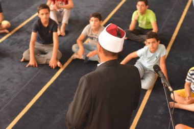 Cairo, Egypt, August 7 2022: A mosque preacher Imam performs a religious Khutbah (sermon) for young Muslim children inside a mosque during the summer Islamic educational program for kids in the mosque