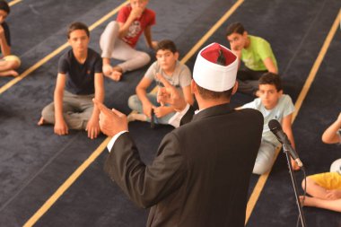 Cairo, Egypt, August 7 2022: A mosque preacher Imam performs a religious Khutbah (sermon) for young Muslim children inside a mosque during the summer Islamic educational program for kids in the mosque