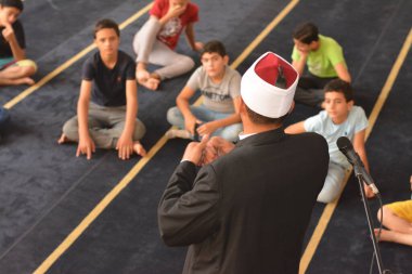 Cairo, Egypt, August 7 2022: A mosque preacher Imam performs a religious Khutbah (sermon) for young Muslim children inside a mosque during the summer Islamic educational program for kids in the mosque