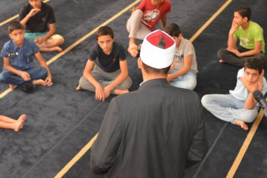 Cairo, Egypt, August 7 2022: A mosque preacher Imam performs a religious Khutbah (sermon) for young Muslim children inside a mosque during the summer Islamic educational program for kids in the mosque