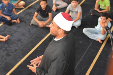 Cairo, Egypt, August 7 2022: A mosque preacher Imam performs a religious Khutbah (sermon) for young Muslim children inside a mosque during the summer Islamic educational program for kids in the mosque
