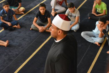 Cairo, Egypt, August 7 2022: A mosque preacher Imam performs a religious Khutbah (sermon) for young Muslim children inside a mosque during the summer Islamic educational program for kids in the mosque