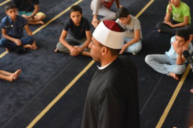 Cairo, Egypt, August 7 2022: A mosque preacher Imam performs a religious Khutbah (sermon) for young Muslim children inside a mosque during the summer Islamic educational program for kids in the mosque