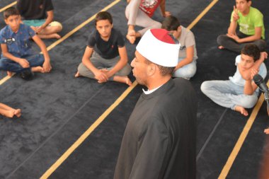 Cairo, Egypt, August 7 2022: A mosque preacher Imam performs a religious Khutbah (sermon) for young Muslim children inside a mosque during the summer Islamic educational program for kids in the mosque
