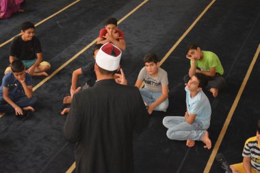 Cairo, Egypt, August 7 2022: A mosque preacher Imam performs a religious Khutbah (sermon) for young Muslim children inside a mosque during the summer Islamic educational program for kids in the mosque