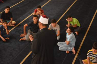 Cairo, Egypt, August 7 2022: A mosque preacher Imam performs a religious Khutbah (sermon) for young Muslim children inside a mosque during the summer Islamic educational program for kids in the mosque