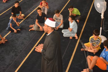 Cairo, Egypt, August 7 2022: A mosque preacher Imam performs a religious Khutbah (sermon) for young Muslim children inside a mosque during the summer Islamic educational program for kids in the mosque