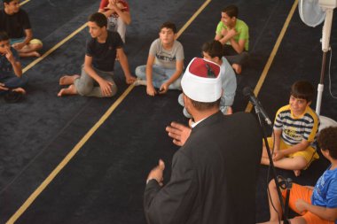 Cairo, Egypt, August 7 2022: A mosque preacher Imam performs a religious Khutbah (sermon) for young Muslim children inside a mosque during the summer Islamic educational program for kids in the mosque
