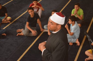 Cairo, Egypt, August 7 2022: A mosque preacher Imam performs a religious Khutbah (sermon) for young Muslim children inside a mosque during the summer Islamic educational program for kids in the mosque
