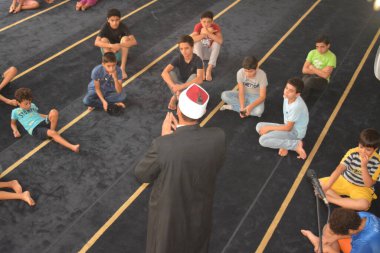 Cairo, Egypt, August 7 2022: A mosque preacher Imam performs a religious Khutbah (sermon) for young Muslim children inside a mosque during the summer Islamic educational program for kids in the mosque