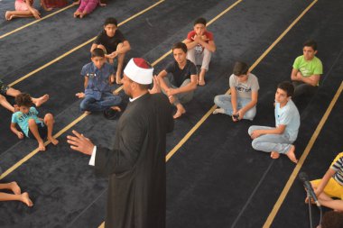 Cairo, Egypt, August 7 2022: A mosque preacher Imam performs a religious Khutbah (sermon) for young Muslim children inside a mosque during the summer Islamic educational program for kids in the mosque