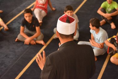Cairo, Egypt, August 7 2022: A mosque preacher Imam performs a religious Khutbah (sermon) for young Muslim children inside a mosque during the summer Islamic educational program for kids in the mosque