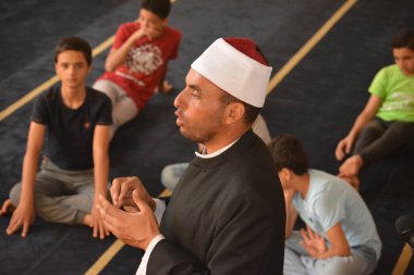 Cairo, Egypt, August 7 2022: A mosque preacher Imam performs a religious Khutbah (sermon) for young Muslim children inside a mosque during the summer Islamic educational program for kids in the mosque