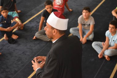 Cairo, Egypt, August 7 2022: A mosque preacher Imam performs a religious Khutbah (sermon) for young Muslim children inside a mosque during the summer Islamic educational program for kids in the mosque