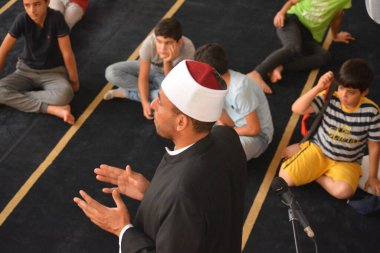 Cairo, Egypt, August 7 2022: A mosque preacher Imam performs a religious Khutbah (sermon) for young Muslim children inside a mosque during the summer Islamic educational program for kids in the mosque