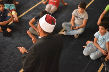 Cairo, Egypt, August 7 2022: A mosque preacher Imam performs a religious Khutbah (sermon) for young Muslim children inside a mosque during the summer Islamic educational program for kids in the mosque